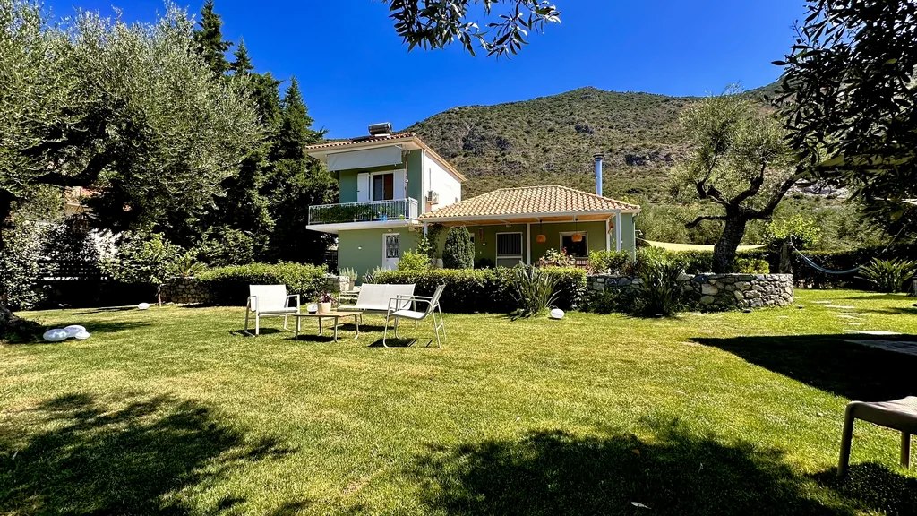 Villa Georgia seen across the lawn, with the olive grove and the mountain behind