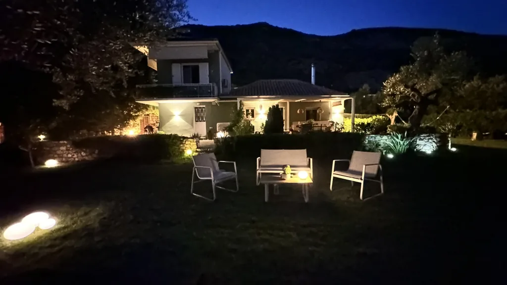 The house lit up at dusk, seen across the lawn